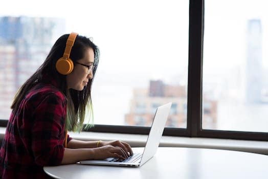 Asian woman with headphones using laptop for remote work in a city setting. website hosting