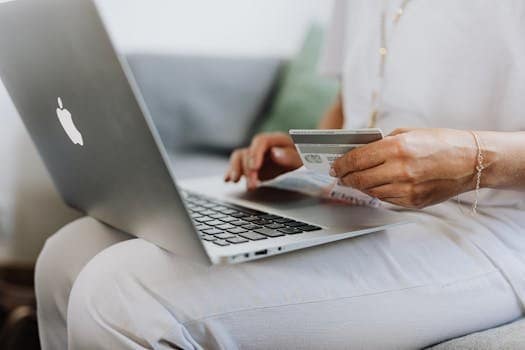 Close-up of a person holding a credit card while shopping online using a laptop at home. home laptops