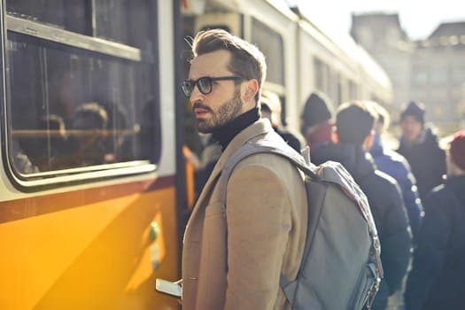 A stylish man with a backpack boards a tram in bustling Budapest, Hungary, during the day. summer clothing.