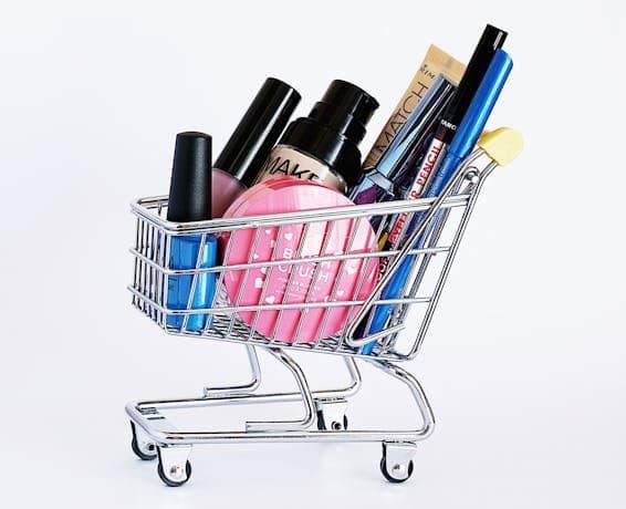 Miniature shopping cart filled with a variety of cosmetics on a white background. Best Value Finds of the Day