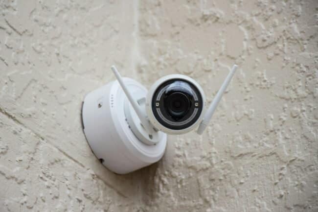 white surveillance camera hanging on wall, security cameras