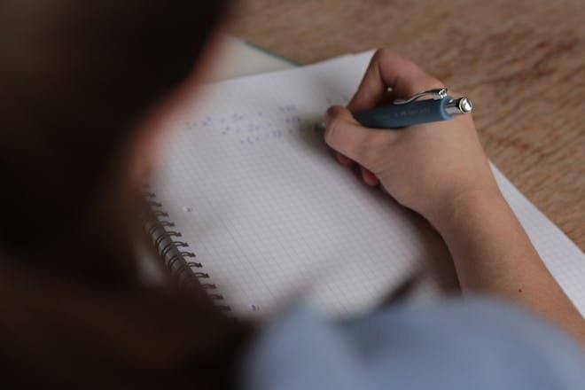 A student writes mathematical notes in a notebook using a pen, focus on studying. TEC Course