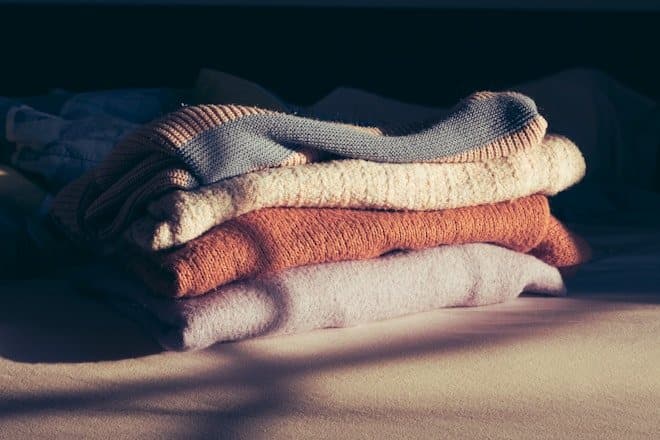 a pile of folded towels sitting on top of a bed. winter products