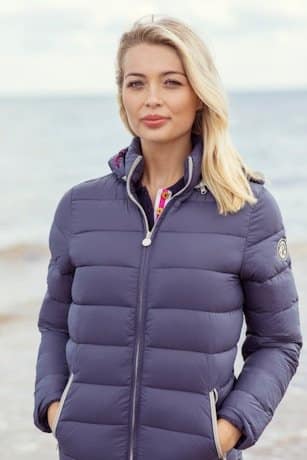 A woman standing on a beach wearing a blue jacket A woman standing on a beach wearing a blue jacket