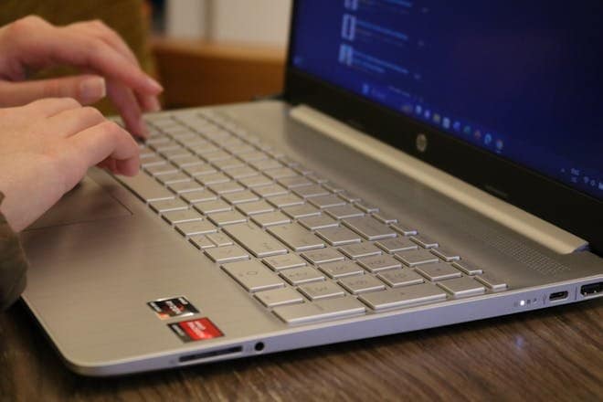 Hands typing on a silver laptop keyboard, showcasing productivity and technology.