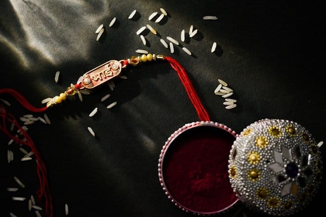 a red and white container with a red string and a red and gold beaded